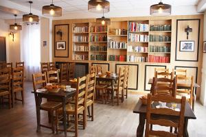 ein Restaurant mit Tischen, Stühlen und Bücherregalen in der Unterkunft Hôtel des Bateliers in La Malène