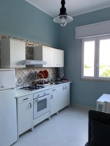 a kitchen with white cabinets and a stove top oven at appartamento VENTO in Pulsano