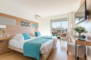 a hotel room with a bed and a desk and a desk at Hôtel Hélios in Juan-les-Pins