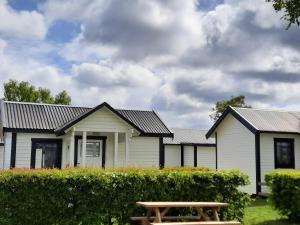 Uma casa branca com uma mesa de piquenique à frente. em Tobisviks Camping em Simrishamn