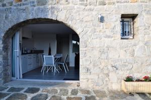 um arco numa parede de pedra com uma mesa e cadeiras em le petit domaine 07 em Les Vans