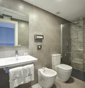 a bathroom with a toilet and a sink and a mirror at Hotel Avenida in Pamplona