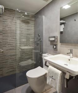 a bathroom with a toilet and a sink and a shower at Hotel Avenida in Pamplona