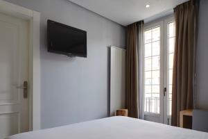 a bedroom with a bed and a television on the wall at Hotel Avenida in Pamplona