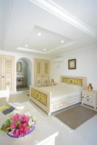 a white bedroom with a large bed and a bowl of flowers at Dar El Yasmine Tunis in Tunis