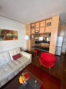 a living room with a white couch and a red stool at Departamento 2 ambientes mas terraza amoblada, Providencia in Santiago