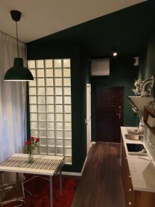 una cocina con paredes verdes y una mesa con un jarrón. en Studio Apartment "Savski Trg", en Belgrado
