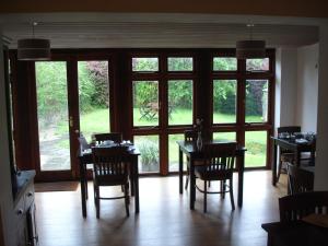 comedor con mesas y sillas y ventanas grandes en Burcott Mill Guesthouse, en Wells