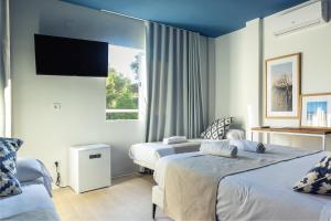 a hotel room with two beds and a flat screen tv at YOU & CO. Saler Beach Boutique in Valencia