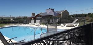 une piscine avec des chaises longues et une maison dans l'établissement Cabañas De Los Tios, à Sierra de la Ventana