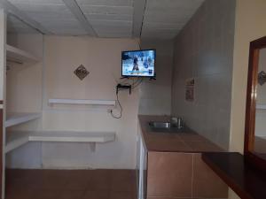 baño con lavabo y TV en la pared en La Casa Azul Hostal y Pension - Coatepec, en Xalapa