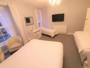 a hotel room with two beds and a television at Anglesey House in Llandudno