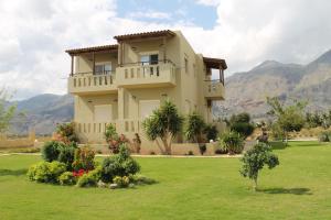 a large house in a field with mountains in the background at Argilos Apartments in Frangokastello