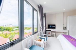 a bedroom with a bed and large windows at Sen Hotel Phu Quoc in Phu Quoc