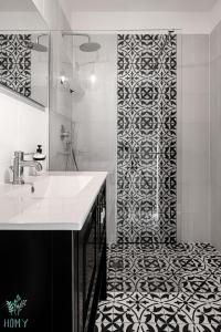 a bathroom with a sink and a black and white patterned wall at HAYARKON - Superior Collection - By HOMY in Tel Aviv