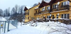 a yellow house with snow on the ground at Zielona Przystań Apartament z widokiem na Pieniny in Jaworki