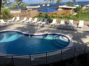 a swimming pool with chairs and umbrellas at Orient Beach Hotel in Orient Bay