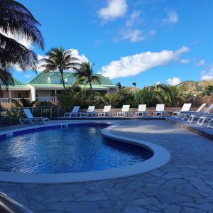 a swimming pool with lounge chairs and palm trees at Orient Beach Hotel in Orient Bay