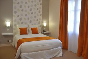 ein Schlafzimmer mit einem großen Bett mit orangefarbenen und weißen Kissen in der Unterkunft Logis Hotels - Château Saint Marcel in Boé