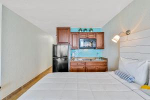 a small kitchen with a black refrigerator and wooden cabinets at Sunshine & Oceanfront Serenity in Daytona Beach Shores