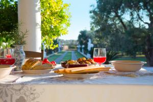 Villa dei Sogni Gallipoli في توليي: طاولة مع أطباق من الطعام وكؤوس من النبيذ