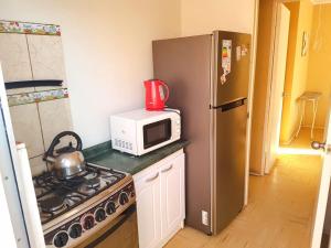 La cocina está equipada con microondas, fogones y nevera. en Casa la serena condominio D. Gabriela en La Serena