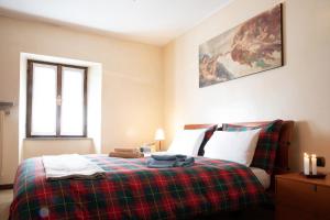 ein Schlafzimmer mit einem Bett mit einer karierten Decke in der Unterkunft Dagli Olivari - Casa Dani in Gromo