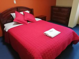 a red bed with red pillows and a red blanket at Hotel Allegria in Quito