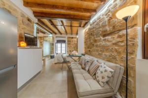 - un salon avec un canapé et un mur en pierre dans l'établissement Apartamentos “Quotidianum”, à Úbeda