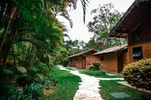 a walkway in front of a house with palm trees at Urikana Boutique Hotel in Teresópolis