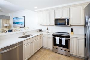 a kitchen with white cabinets and a sink and a stove at Bellasera Resort in Naples