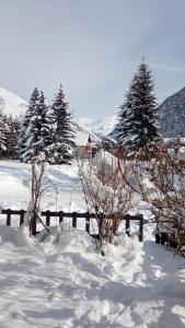 un champ enneigé avec des arbres et une clôture dans l'établissement Studio Residence Le Stella, à Ancelle