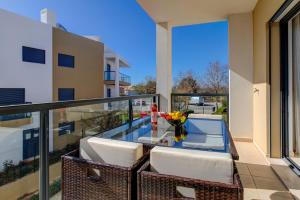 a balcony with a glass table and white chairs at One Bedroom Apartment in Albur Village 1A in Alvor