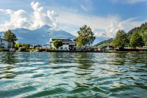 a body of water with buildings and mountains in the background at Junges Hotel Zell am See in Zell am See