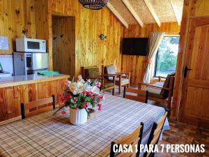 a dining room with a table with flowers on it at Cabañas Villangel Licanray in Licán Ray