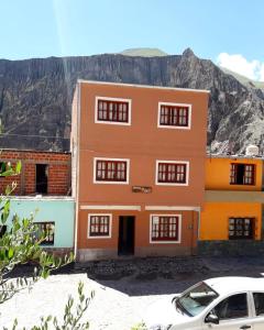 een oranje gebouw met een auto ervoor geparkeerd bij HOSTAL LA PLAZA IRUYA in Iruya