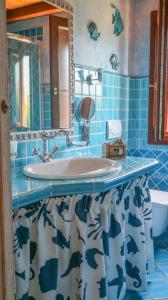 Un baño con azulejos azules, lavabo y espejo. en Aria, en Budoni