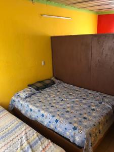 a bed in a room with a yellow wall at Cabaña Quiahuiztlán Playa Villa Rica in Laguna Verde