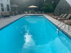 a blue swimming pool with chairs and an umbrella at Goldberry Woods- A Modern Farm Resort in Union Pier