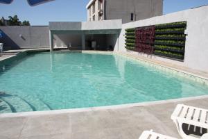 a large swimming pool with two white chairs in front of a building at Hotel Foz do Iguaçu in Foz do Iguaçu