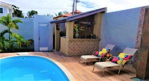 um pátio com 2 cadeiras e uma piscina em Excelente Duplex em Arembepe Aquaville - Bahia em Salvador
