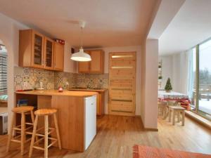a kitchen with wooden cabinets and a kitchen island with stools at Chata Bieszczady in Wetlina