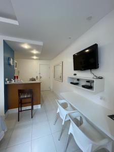 a living room with a table and a tv on the wall at Apartamentos em Ipanema in Rio de Janeiro