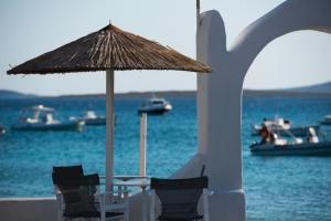 a table and chairs with an umbrella on the beach at Ostria Studios & Apartments in Aliki