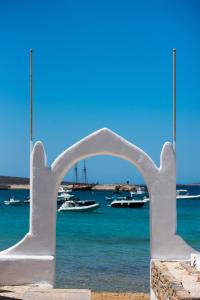 a white arch with boats in the water at Ostria Studios & Apartments in Aliki