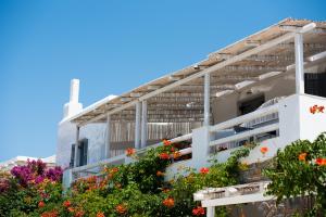 a white building with flowers in front of it at Ostria Studios & Apartments in Aliki