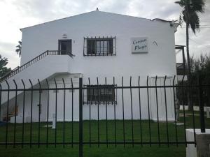 Ein weißes Gebäude mit einem Zaun davor. in der Unterkunft Apartamentos Corona Playa in Playa del Ingles
