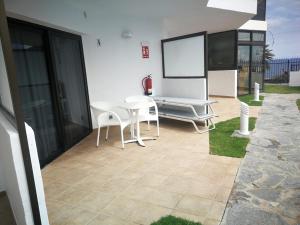 eine Terrasse mit einem weißen Tisch und Stühlen sowie einem Bildschirm in der Unterkunft Apartamentos Corona Playa in Playa del Ingles