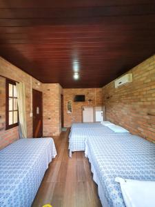a room with two beds and a brick wall at Pousada do Riacho in Barreirinhas