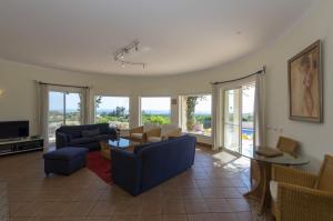 uma sala de estar com sofás, uma mesa e cadeiras em Villa with beautiful see views & spacious garden em Ferragudo